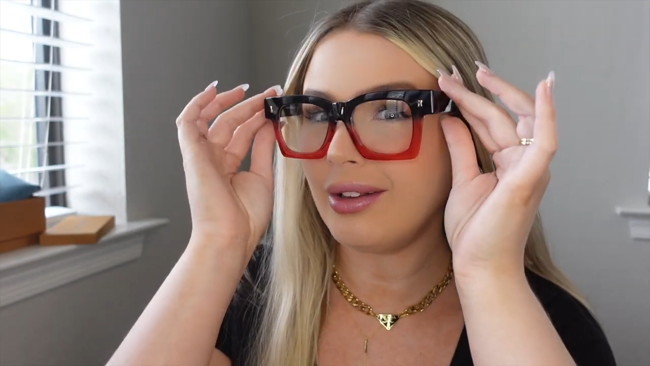 Michaela adjusting Amidala bold color - block glasses, featuring thick black - top and red - bottom frame, an edgy statement piece for trendsetters.