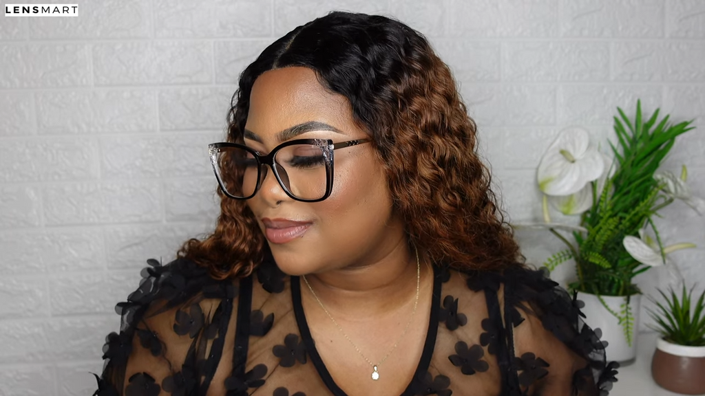 Mimi Manaso looks off to the side with a soft smile while modeling the Lyric glasses by Lensmart, whose sophisticated black and gold frames give her a professional, 'boss babe' look.