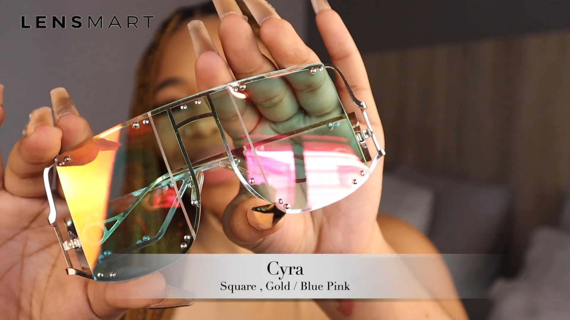 Salome Laka holding Lensmart Cyra sunglasses, showcasing square - shaped, gold - framed glasses with blue - pink lenses that blend style and functionality.