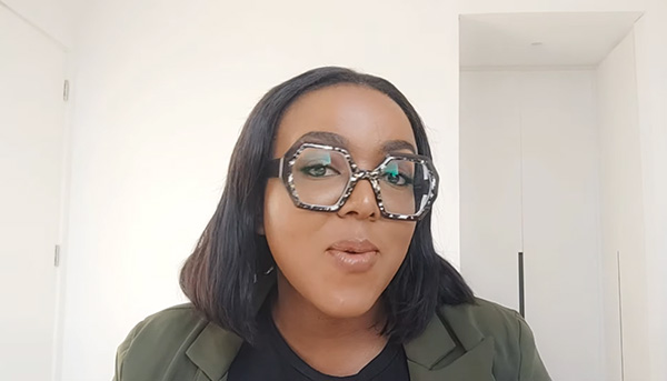 Namolinah in Lensmart Siobhan glasses, showcasing large exaggerated frames & a bold chain for a fashion statement.