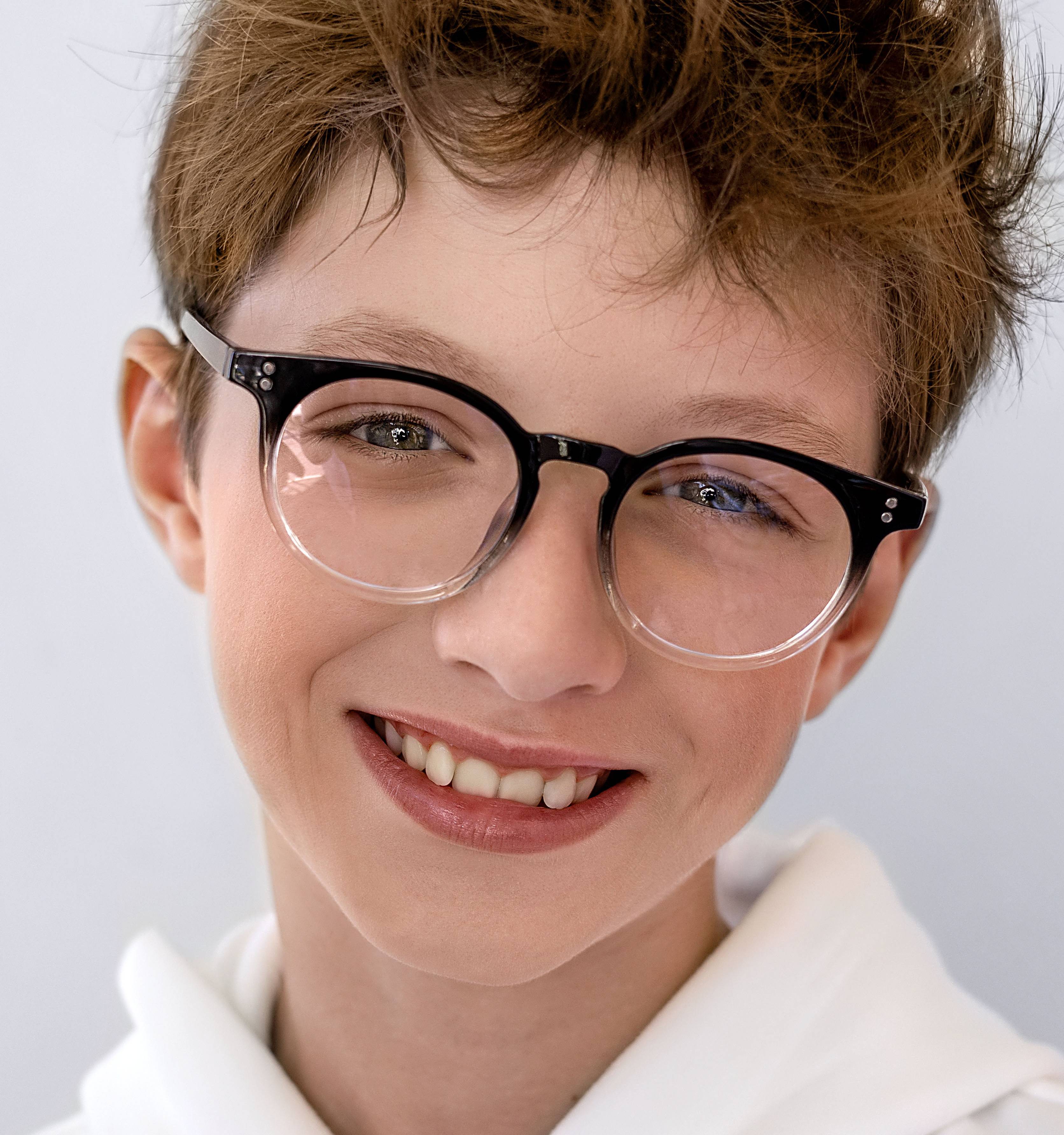 Smiling boy in black-and-white glasses and a white hoodie.